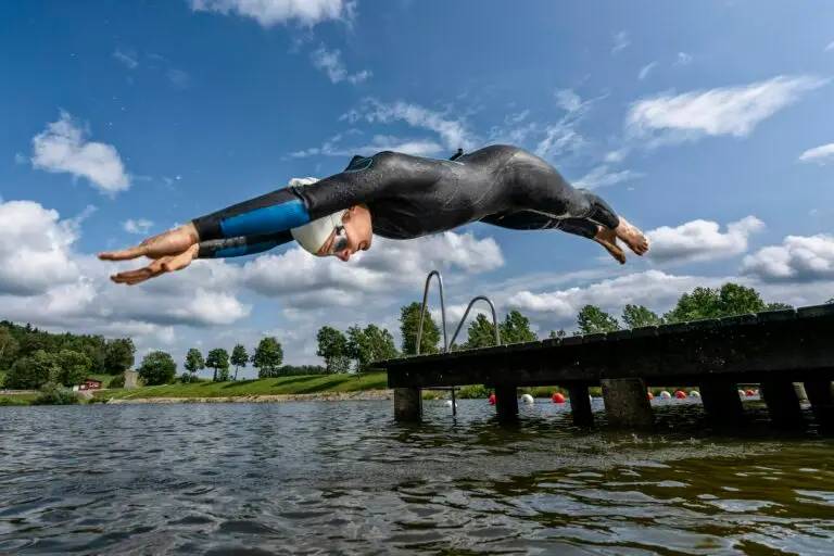 Young female triathlete jumping into a lake